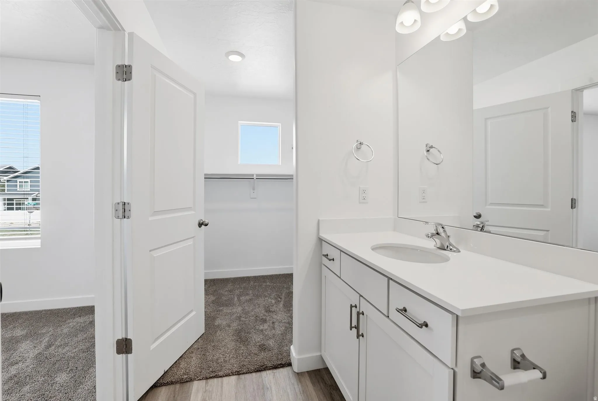 Bathroom vanity with a single undermount sink, white countertop, and light wood-finish flooring