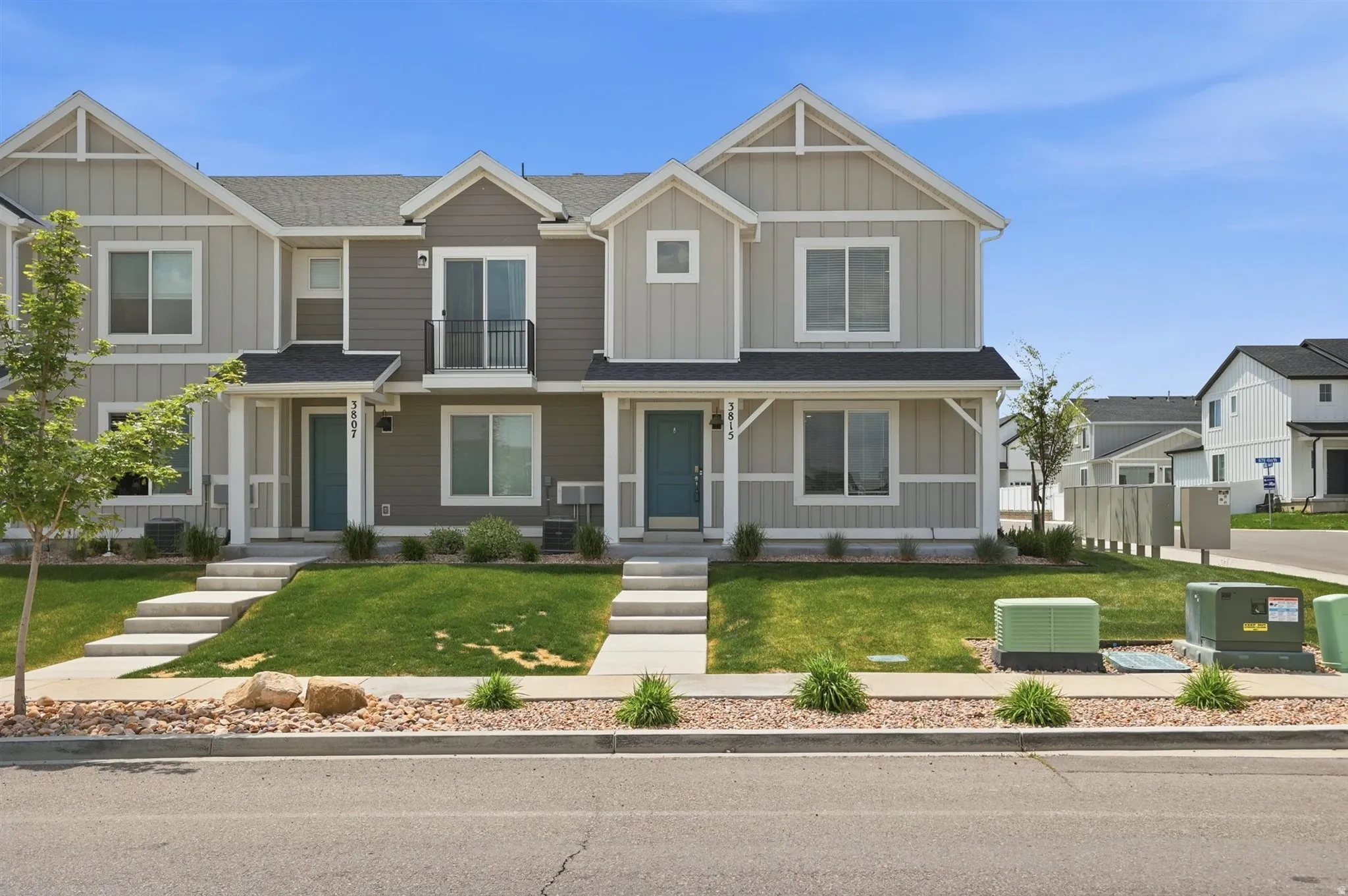 Contemporary townhome exterior featuring light-colored siding with dark accents and a dark roof