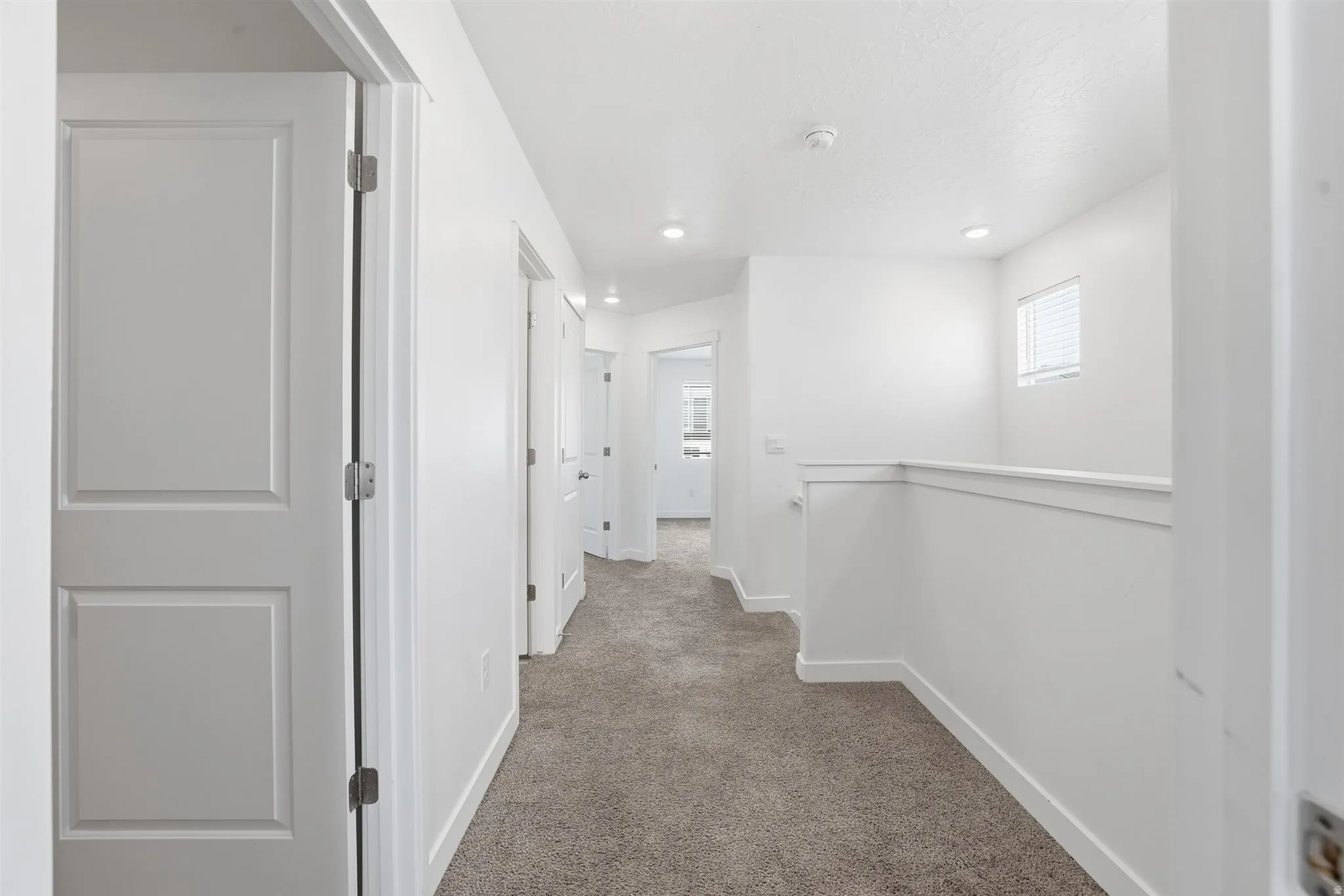 Upper-level hallway with textured carpeting, recessed lighting, and white paneled doors