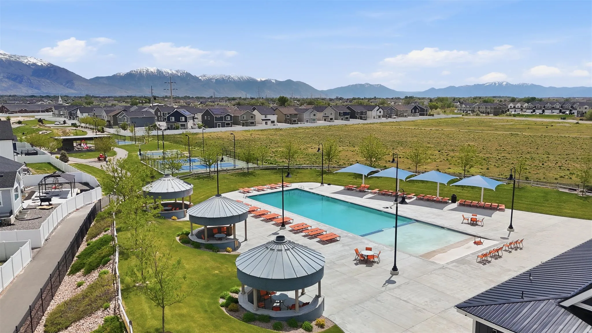Outdoor swimming pool with integrated sun shelf, concrete surround, three covered gazebos, and multiple sun loungers