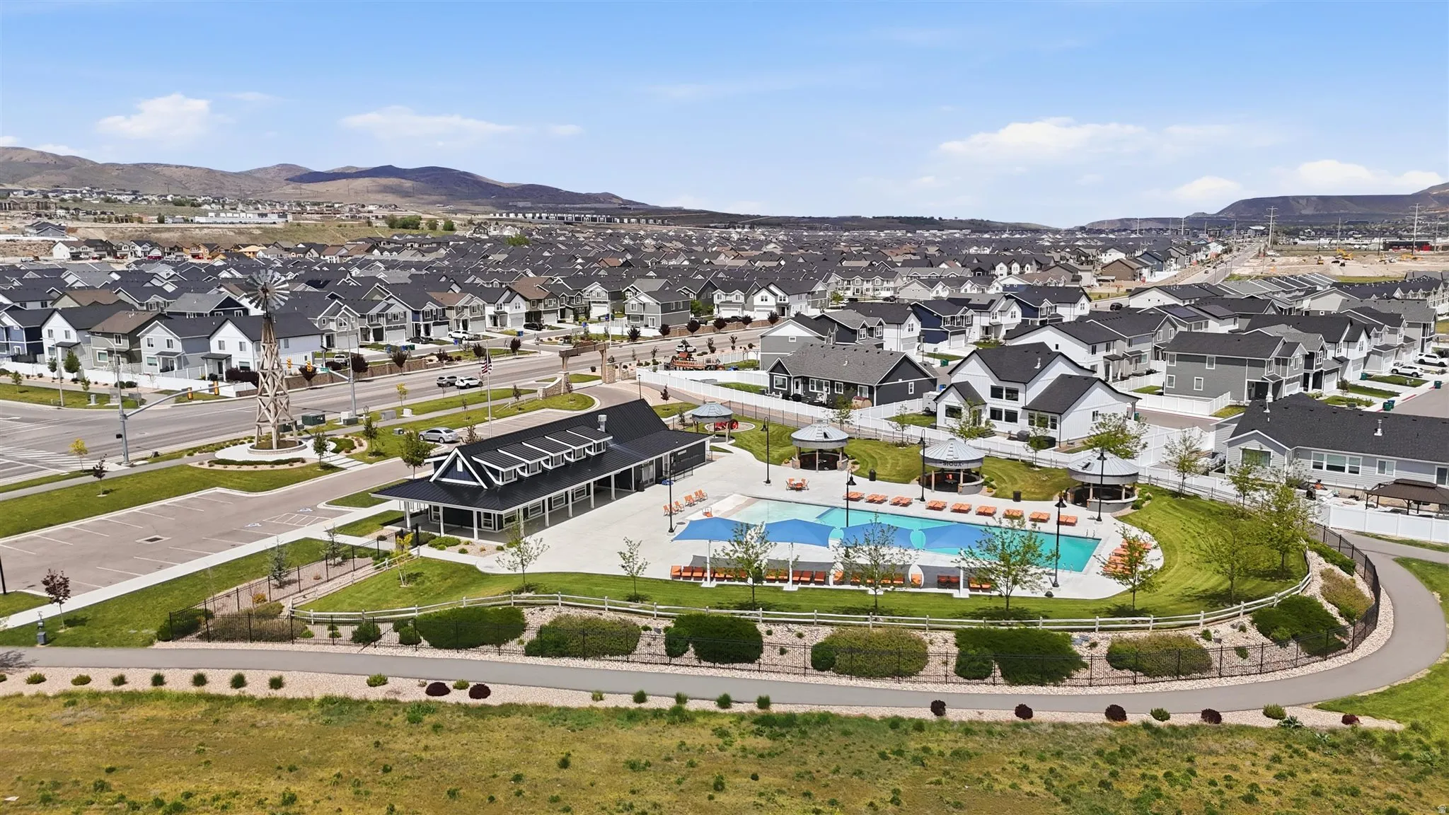Community gathering area featuring a swimming pool with integrated lounge seating, surrounding cabanas, and a dedicated clubhouse building