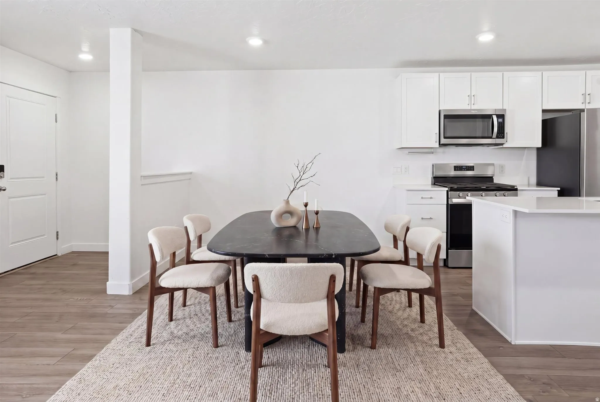 Open-concept dining area featuring wood-finish flooring, recessed lighting, and a white interior door