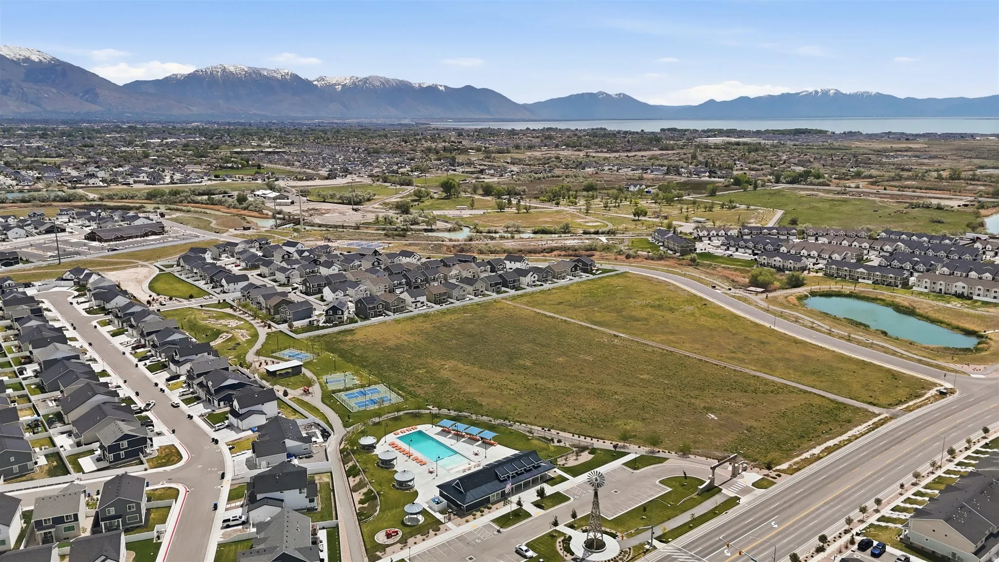 Aerial perspective showcasing a residential development with a community pool, sports courts, and green spaces