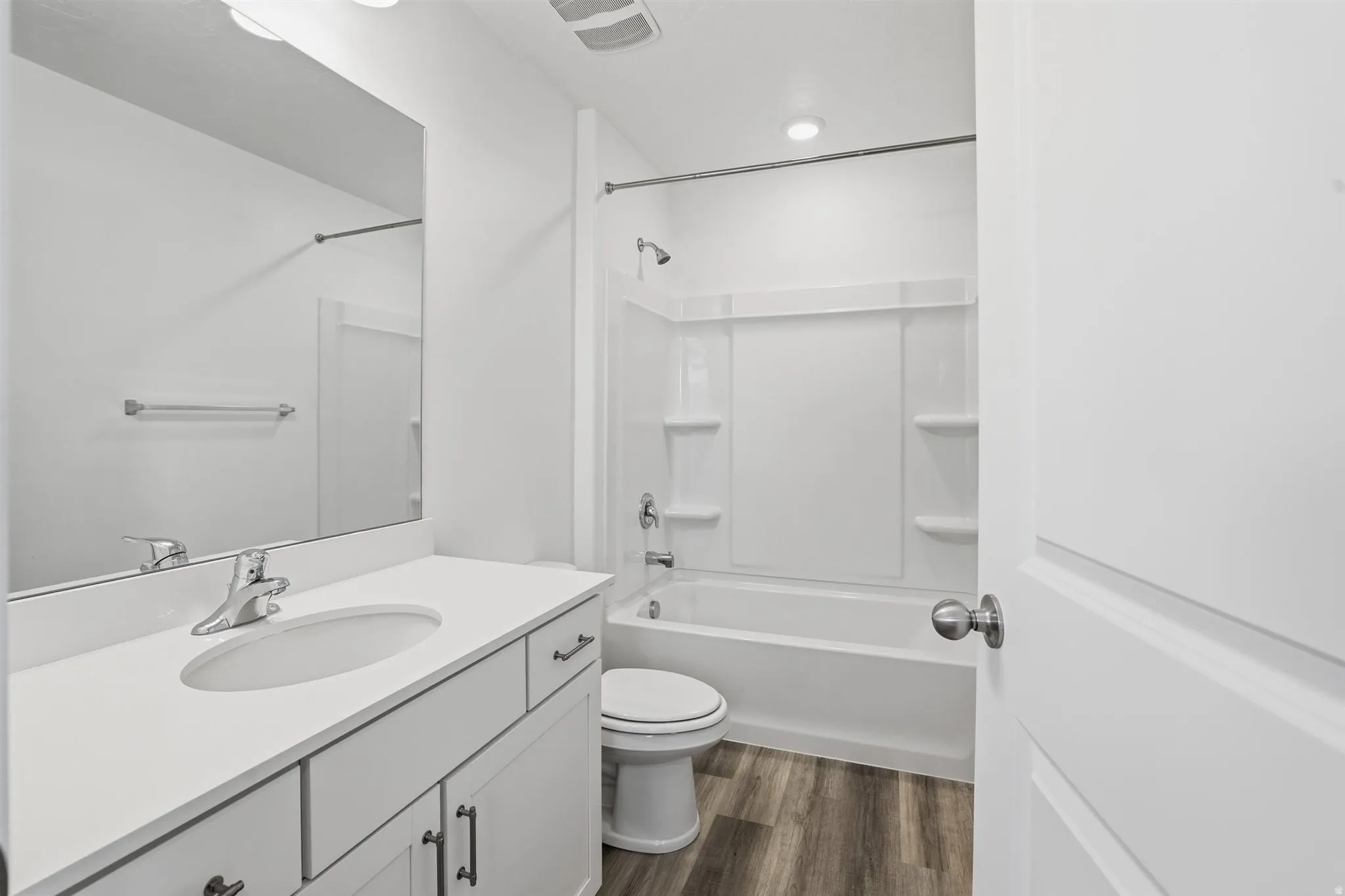 Bathroom featuring a vanity with an integrated sink, polished chrome faucet, white cabinetry with dark hardware, and a large wall-mounted mirror