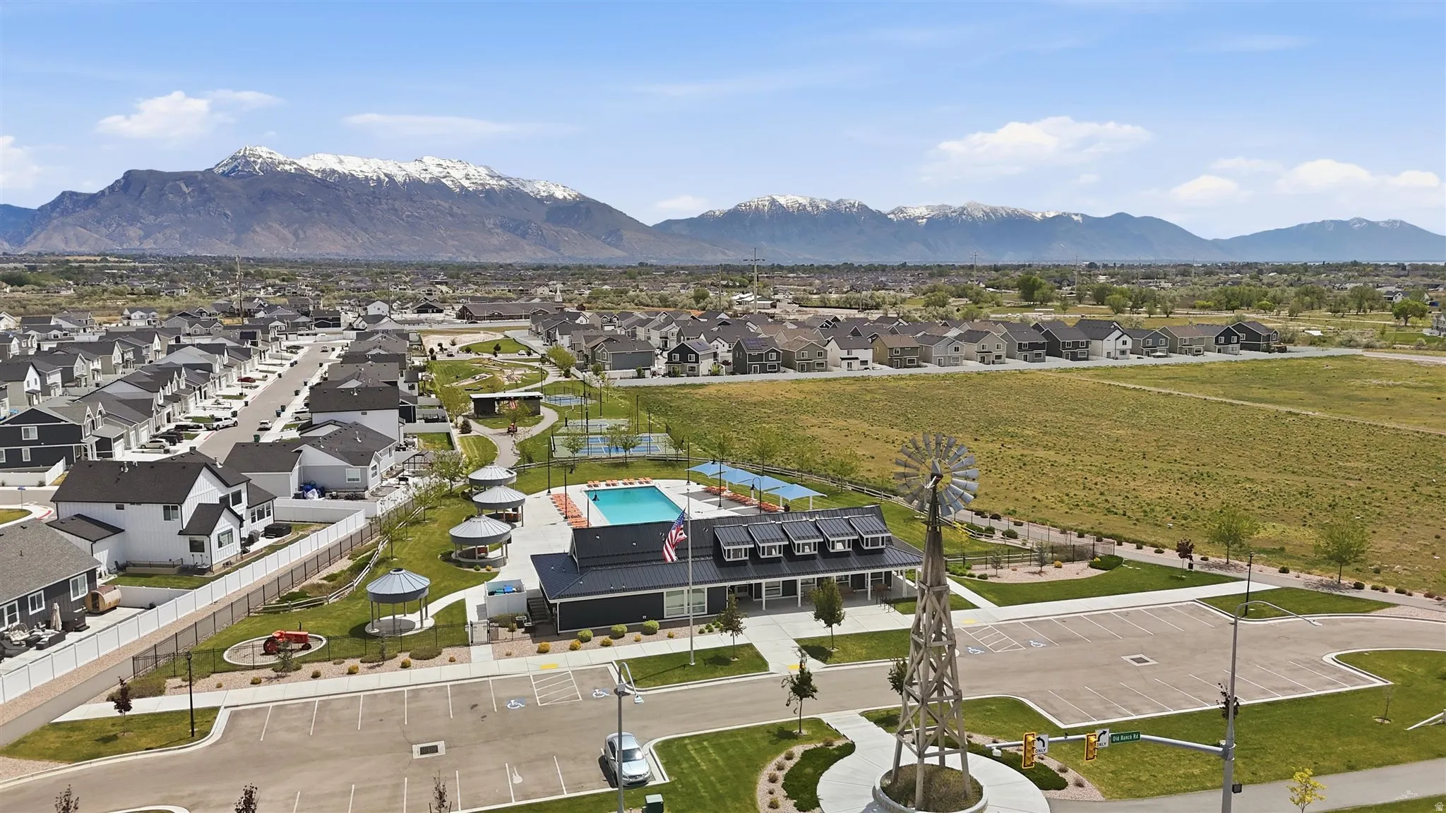 Community park with a swimming pool, covered gazebos, and recreation courts framed by mountain scenery
