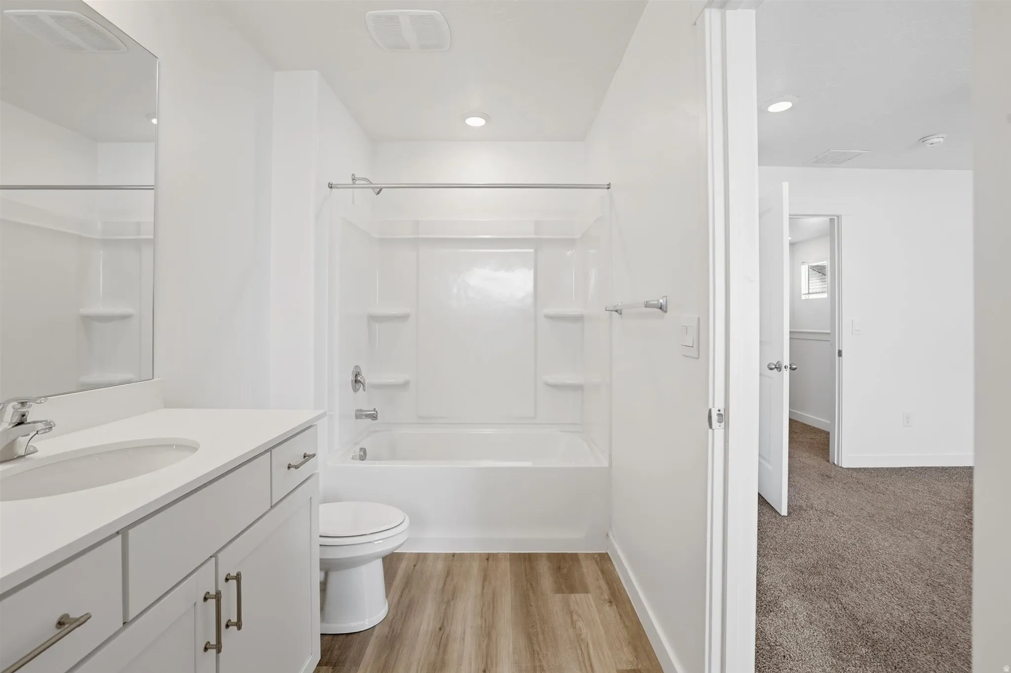 Bathroom featuring a white vanity with an integrated sink, polished chrome faucet, and a large mirror