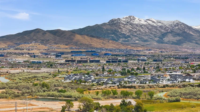 Expansive aerial perspective showcasing a suburban landscape with a prominent snow-capped mountain range in the background