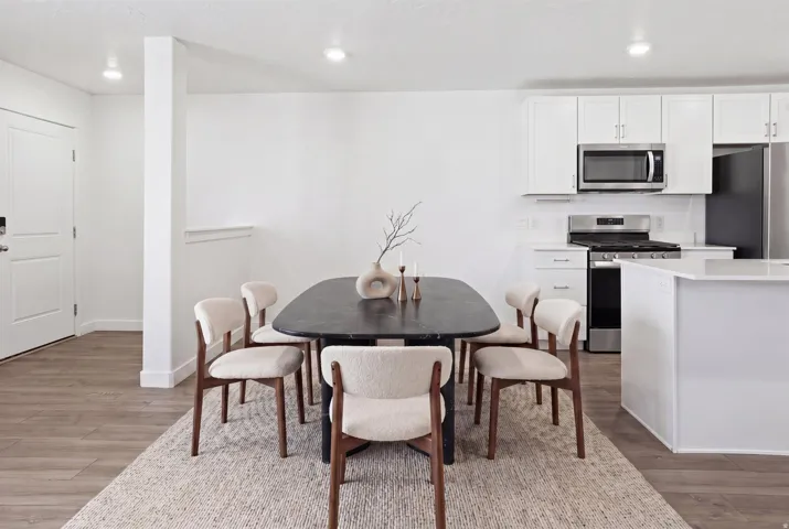 Open-concept dining area featuring wood-finish flooring, recessed lighting, and a white interior door