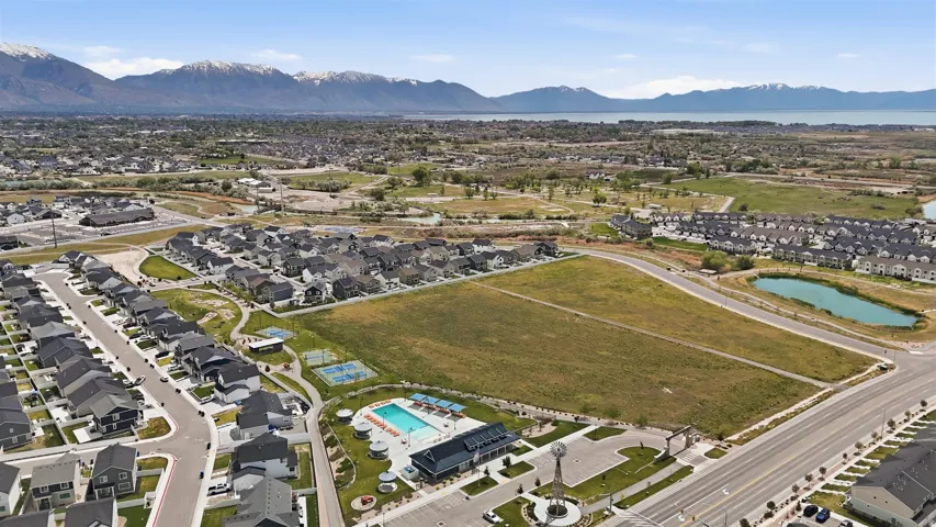 Aerial perspective showcasing a residential development with a community pool, sports courts, and green spaces