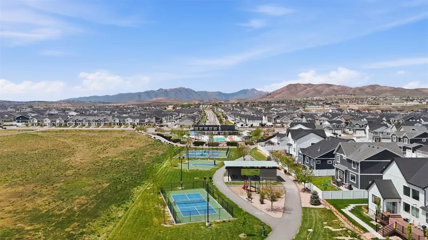 Aerial perspective showcasing a residential community with contemporary homes, two tennis courts, and a playground area with a covered structure
