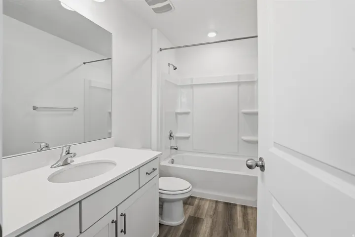 Bathroom featuring a vanity with an integrated sink, polished chrome faucet, white cabinetry with dark hardware, and a large wall-mounted mirror