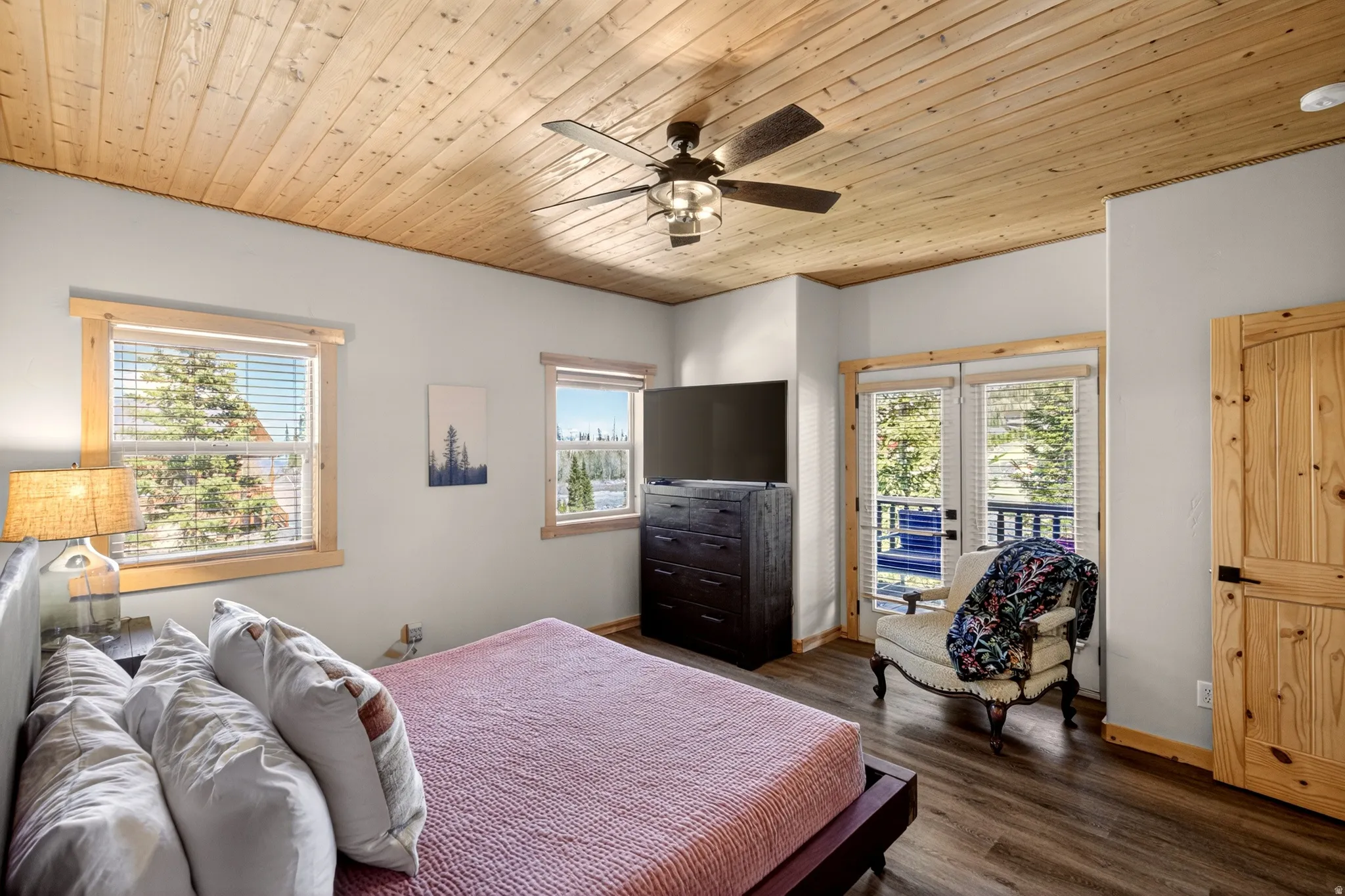 Room featuring a wood-panel ceiling with a ceiling fan, dual windows, and wood-finish flooring