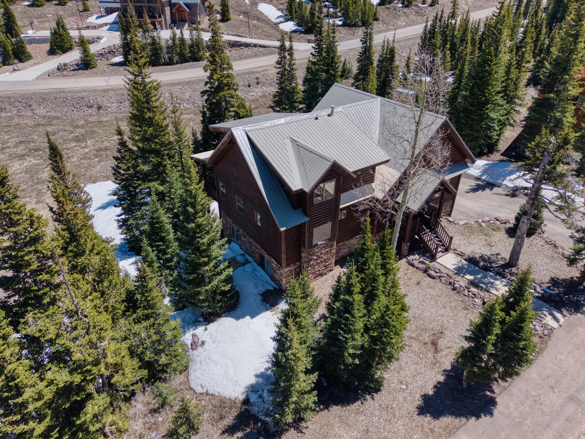 Rustic-style residence featuring a brown wood-paneled exterior, stone accents, and a gray metal roof