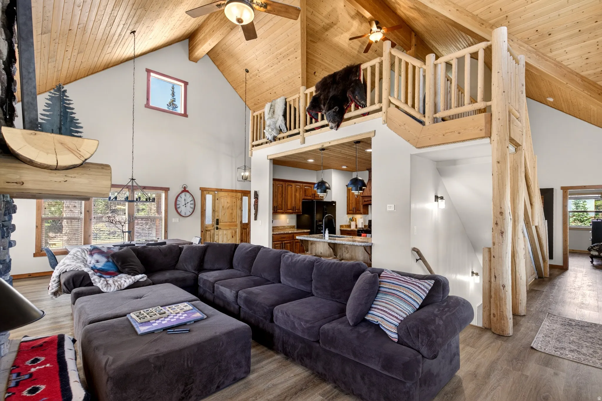 Vaulted wood-paneled ceilings with exposed beams, an open loft area with log railings, and a prominent stone fireplace