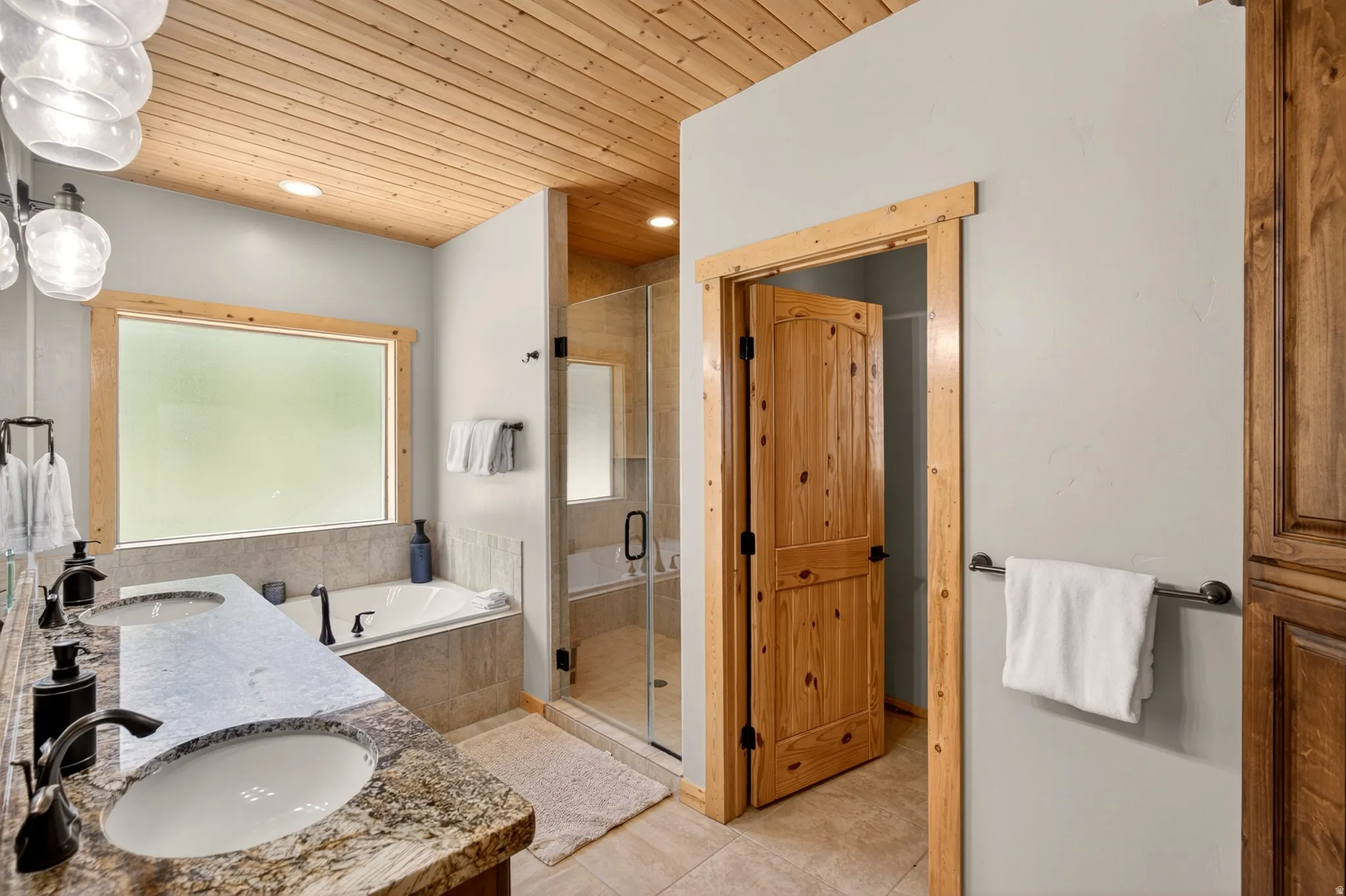 Dual vanity with granite-finish countertop and undermount sinks, alongside a jetted soaking tub