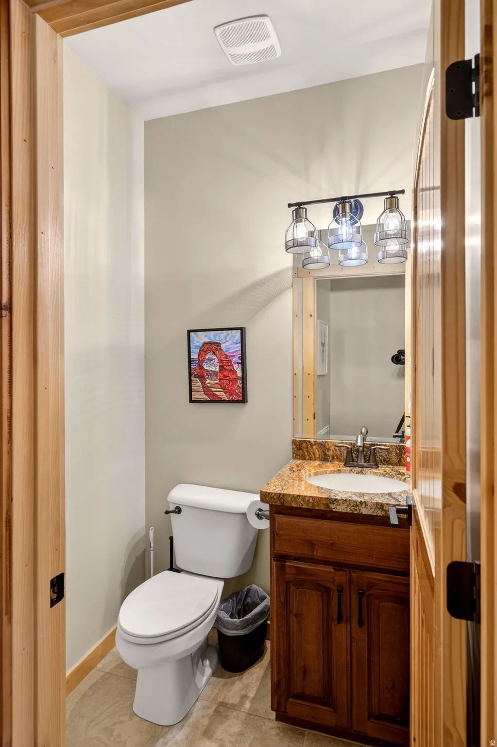 Compact bathroom featuring a vanity with a stone-finish countertop, undermount sink, and dark wood-finish cabinetry