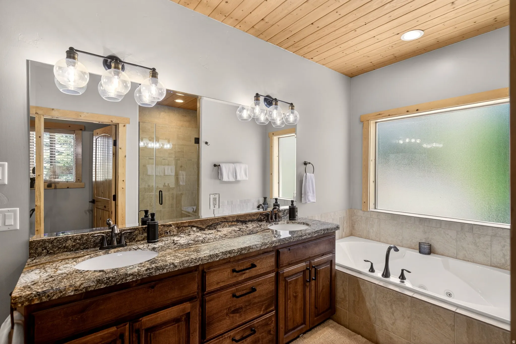 Dual vanity with granite countertop and undermount sinks, accompanied by a built-in jetted tub