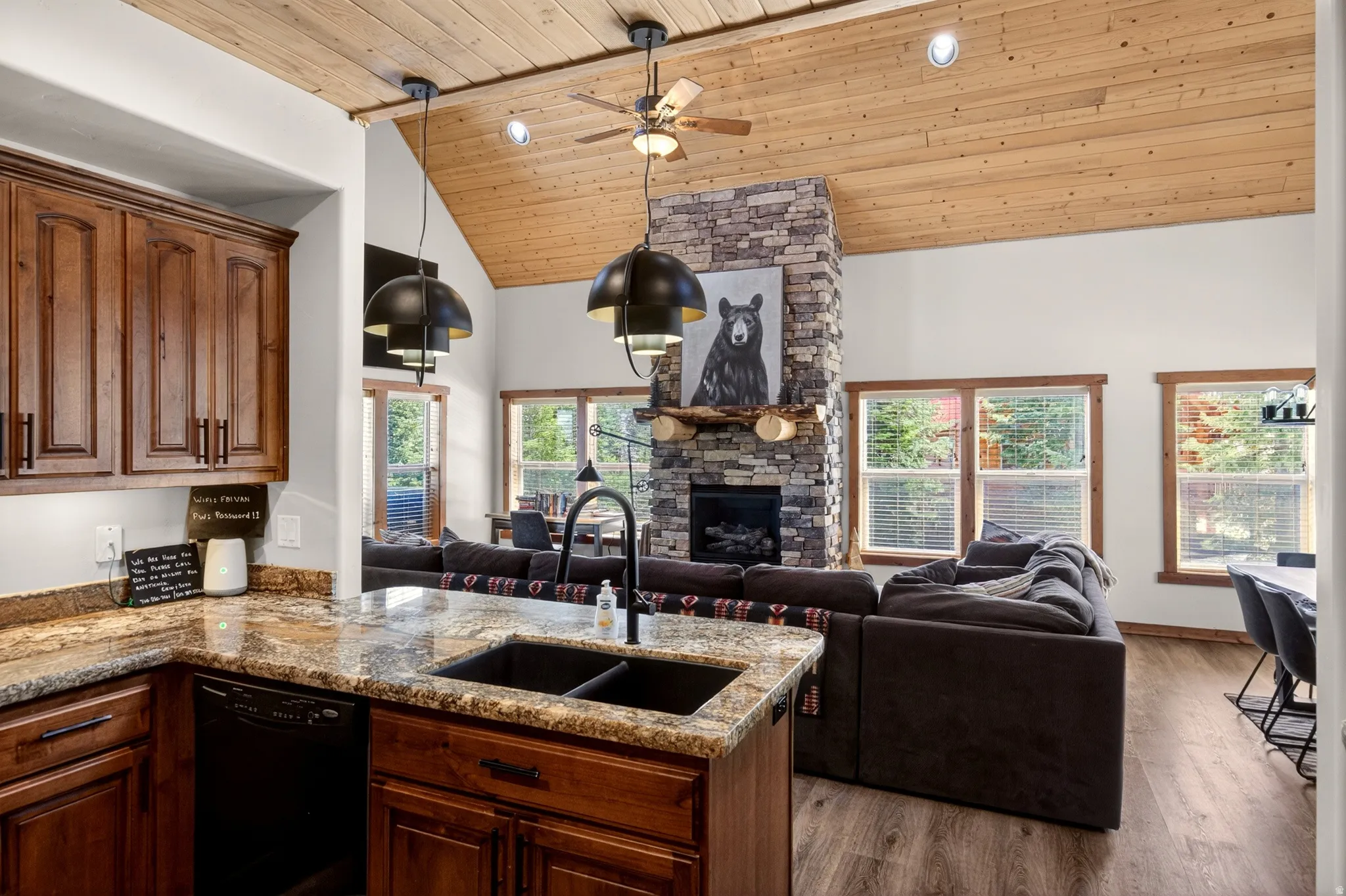 Kitchen island with a double basin sink and a high-arc faucet, rich wood cabinetry, and granite countertops
