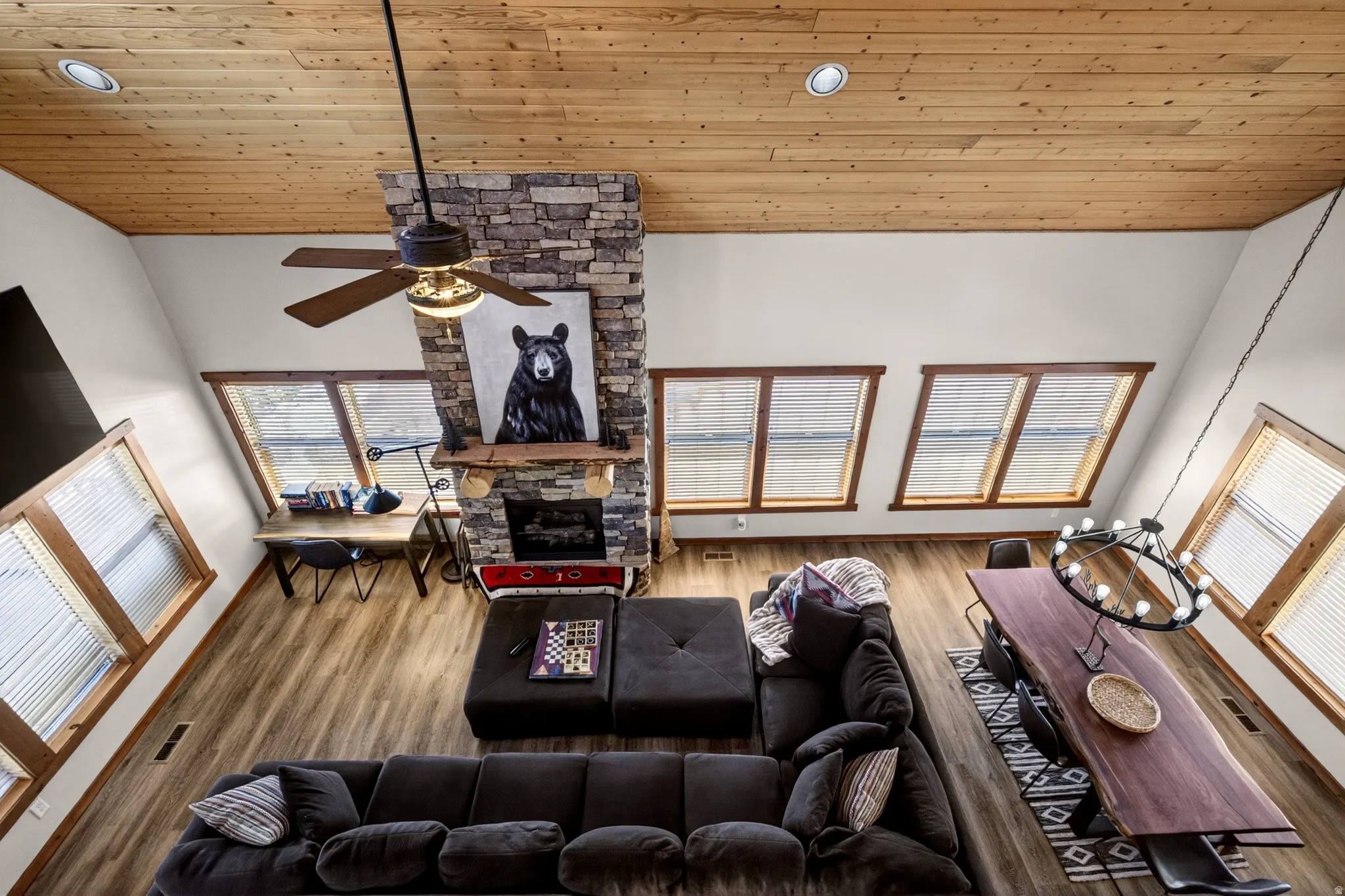 Spacious living area featuring a stone fireplace, wood-finish flooring, and a natural wood plank ceiling