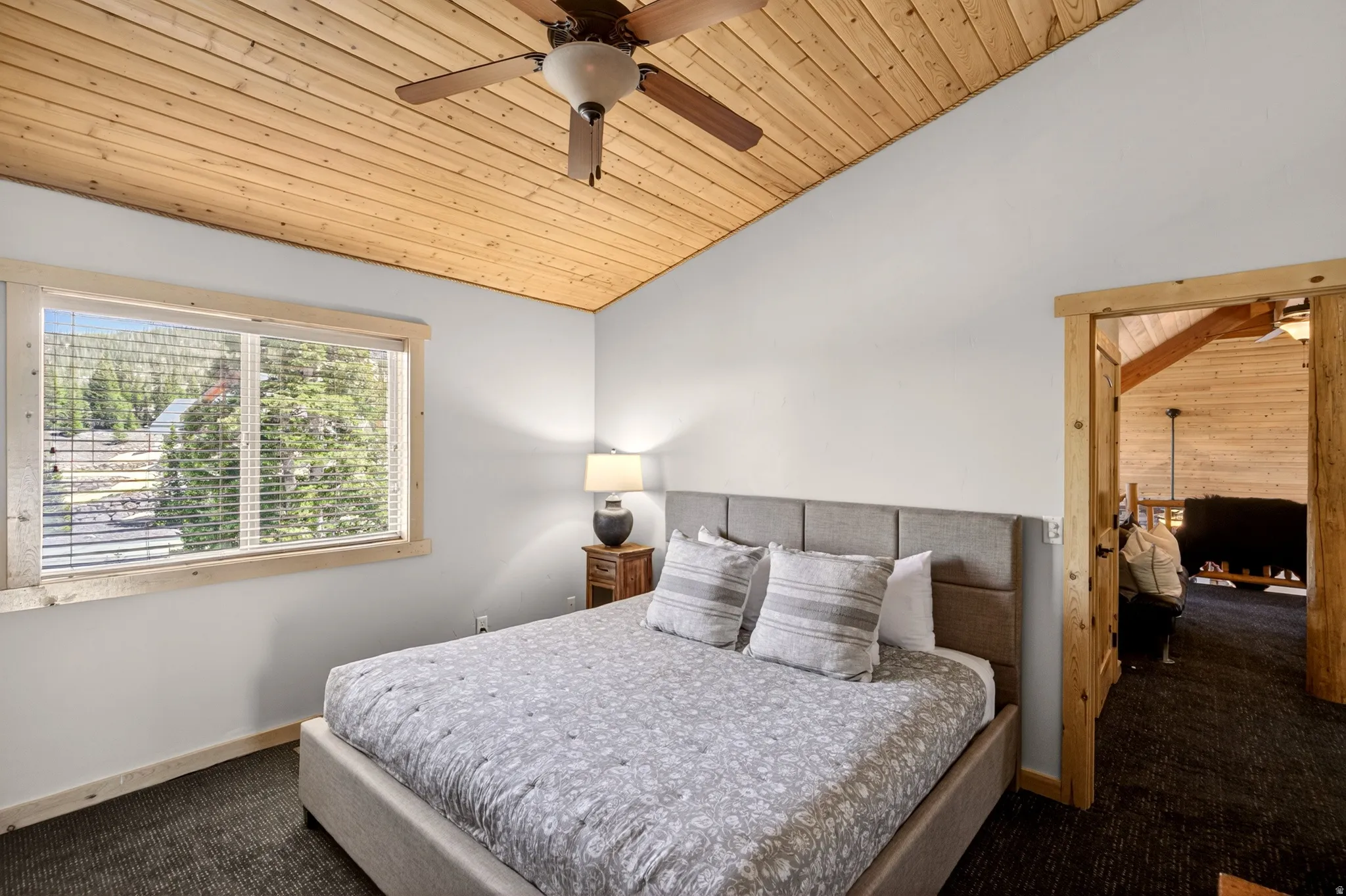 Vaulted wood-paneled ceiling with a ceiling fan, a window with blinds, and a wood-trimmed doorway