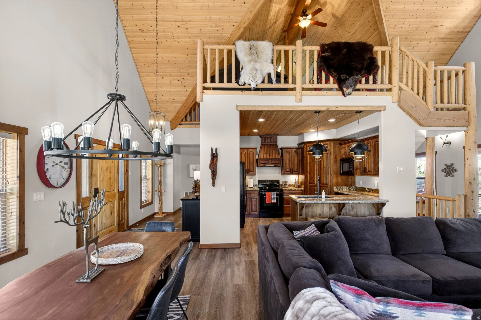 Vaulted wood-paneled ceilings with exposed beams, wood-finish flooring, and a lofted area with log railing