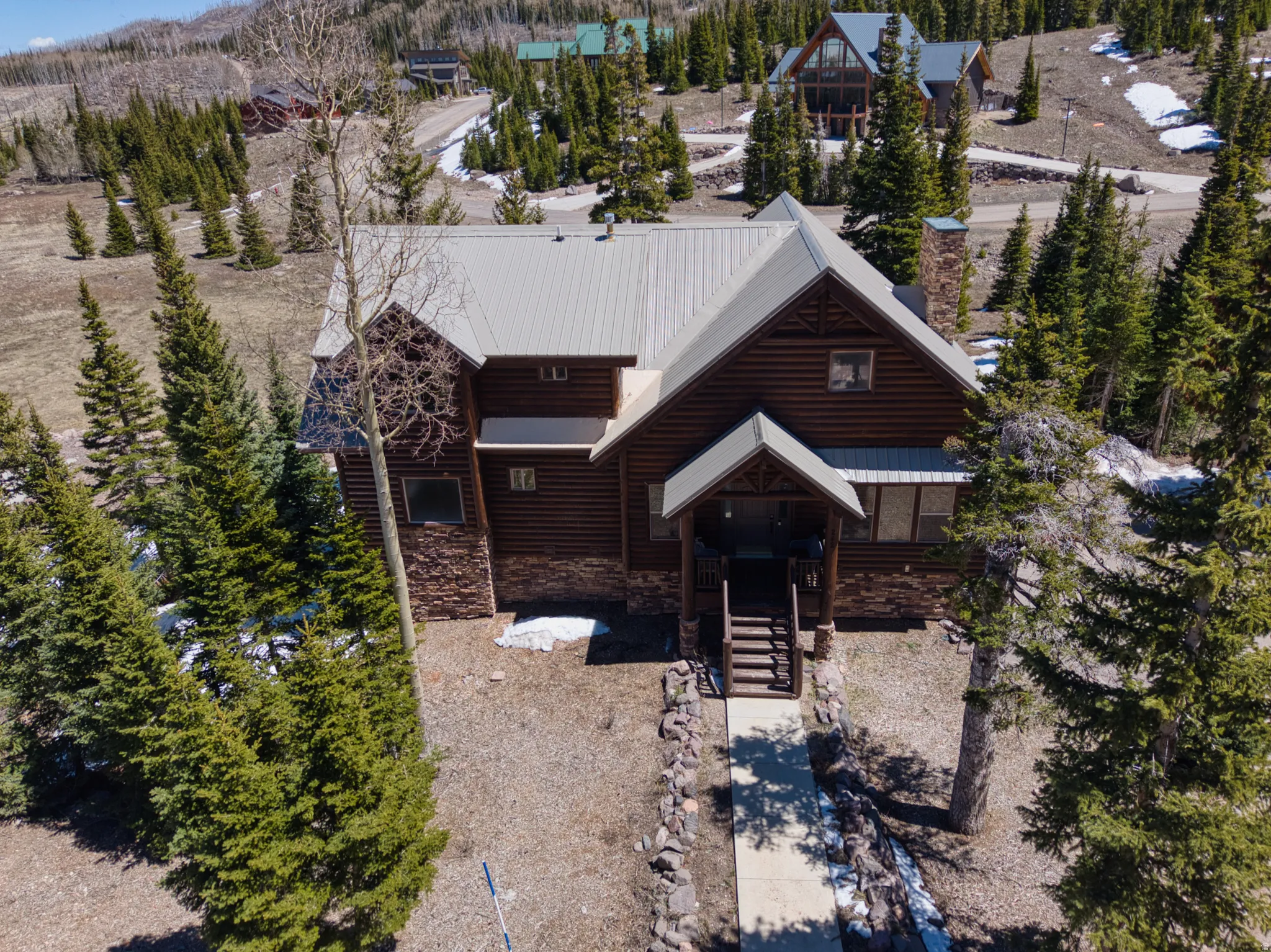 Mountain-style home featuring log siding, stone accents, and a metal roof