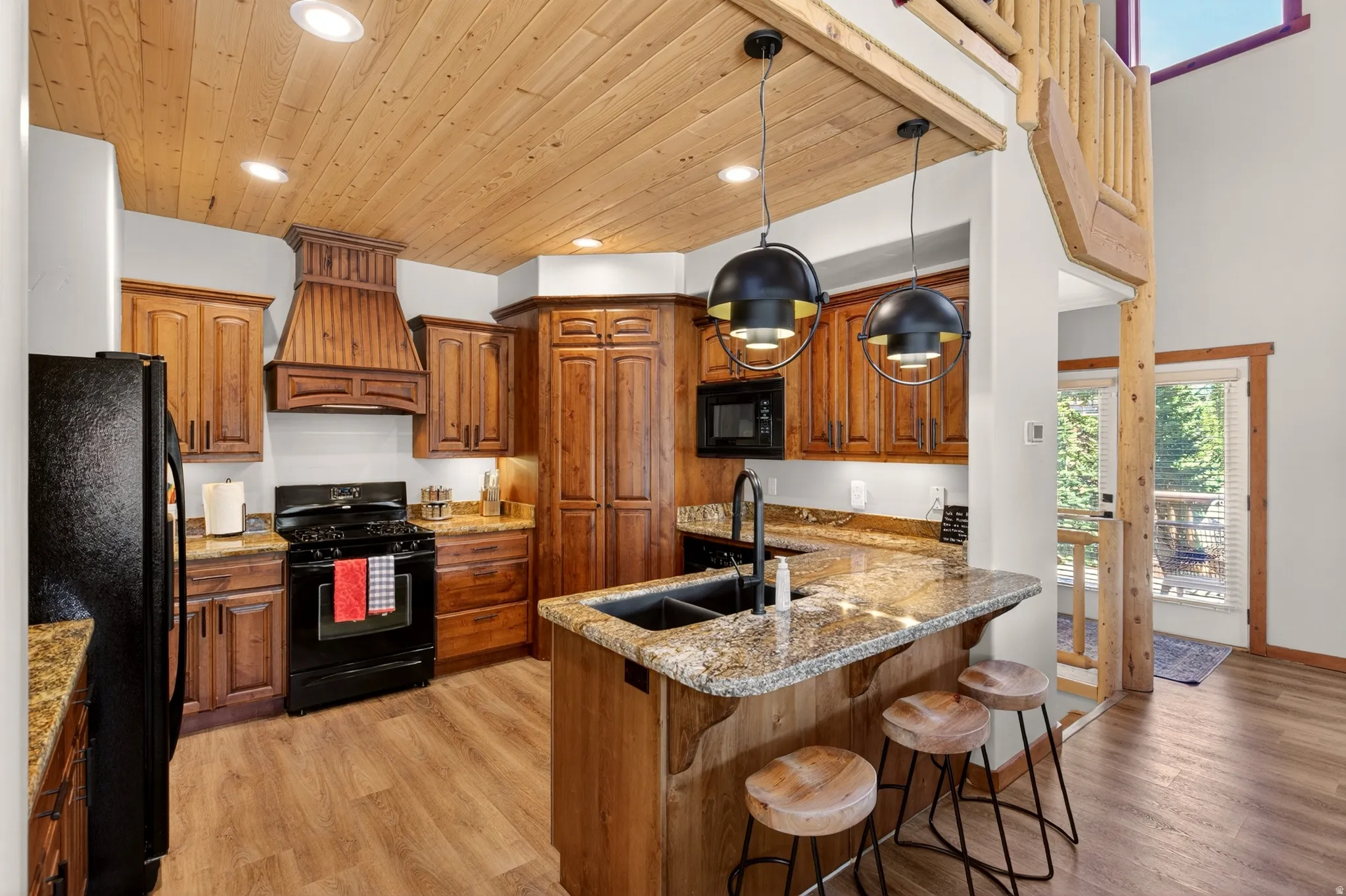 Well-appointed kitchen featuring wood-finish cabinetry, granite countertops, and a wood-planked ceiling