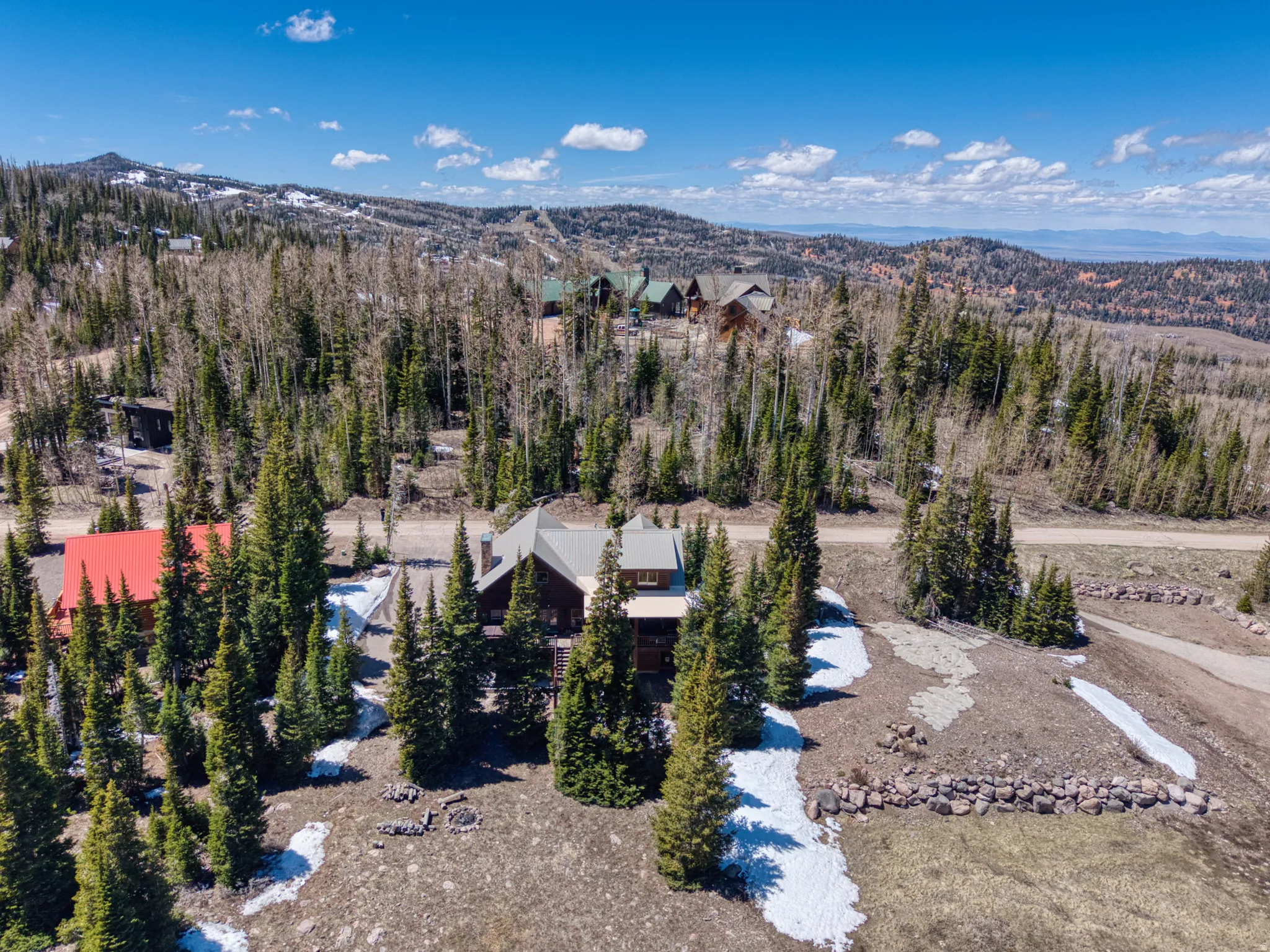 Mountain property featuring a multi-level structure with a gabled roof, surrounded by evergreen trees