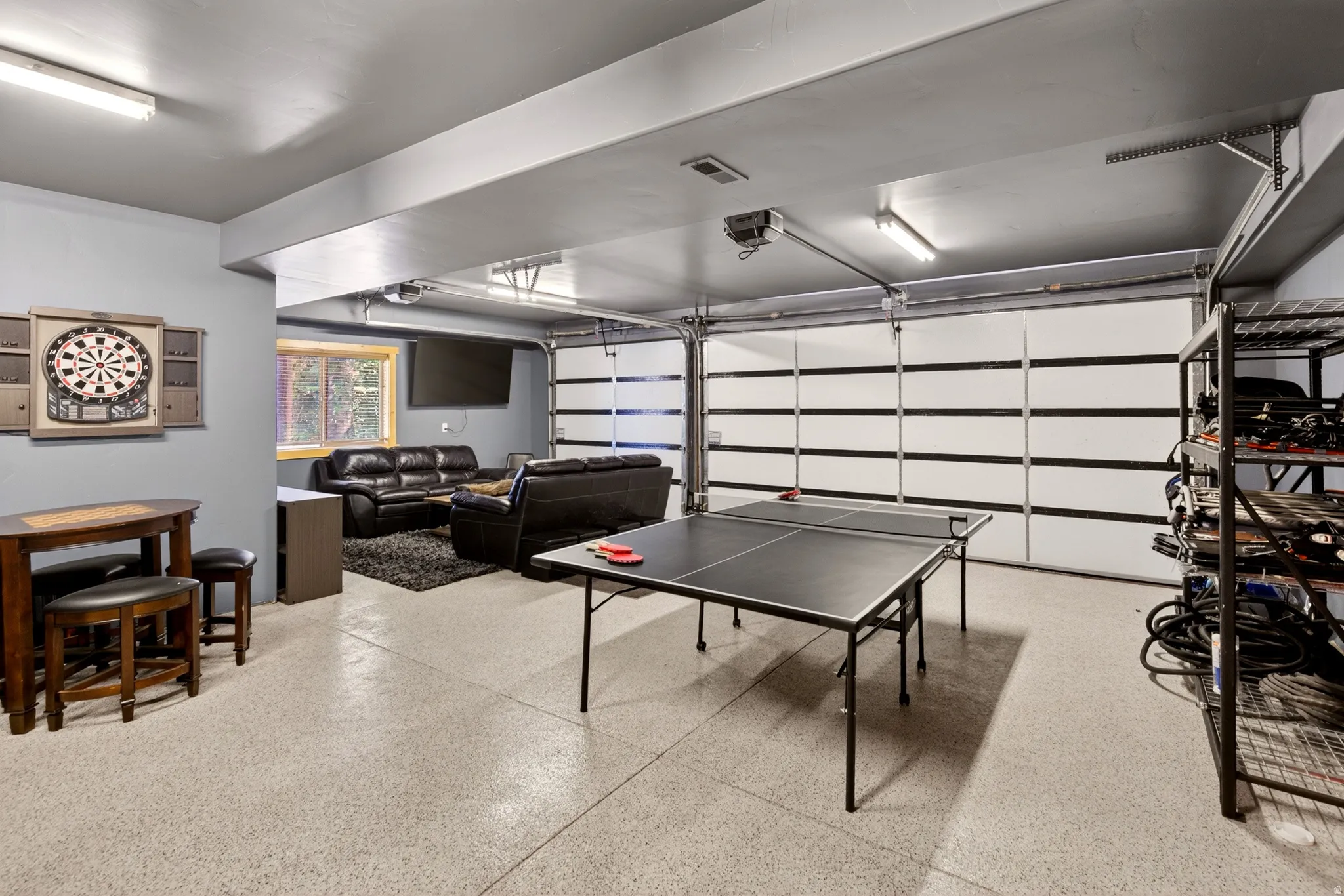 Expansive multi-purpose space featuring epoxy flooring, overhead lighting, and a modern garage door