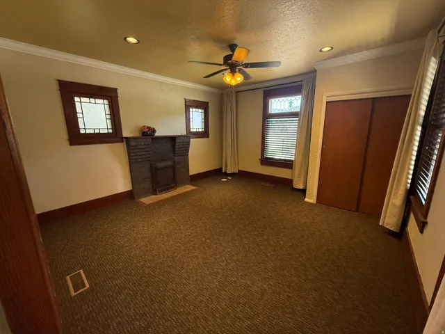Brick fireplace with hearth, wood-trimmed windows, recessed lighting, and a ceiling fan
