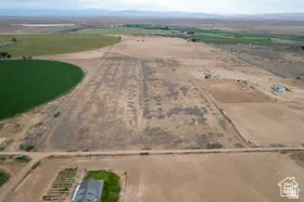 Expansive agricultural land featuring a circular irrigated field, multiple cultivated plots, and distant farm structures