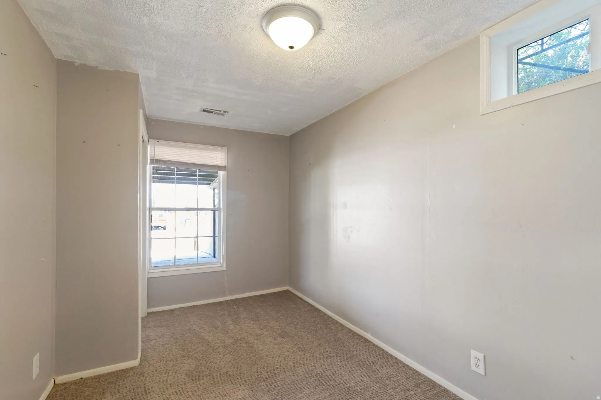 Neutral-toned interior room featuring light gray walls and a textured ceiling