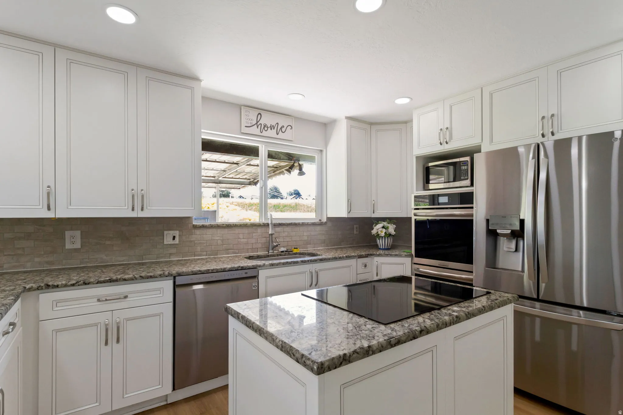 Contemporary kitchen featuring white cabinetry, stone countertops, a mosaic tile backsplash, and recessed lighting