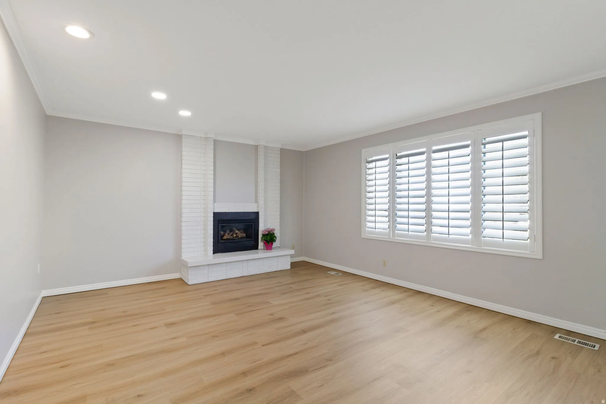 Living area featuring wood-look flooring and a white brick fireplace with a dark firebox