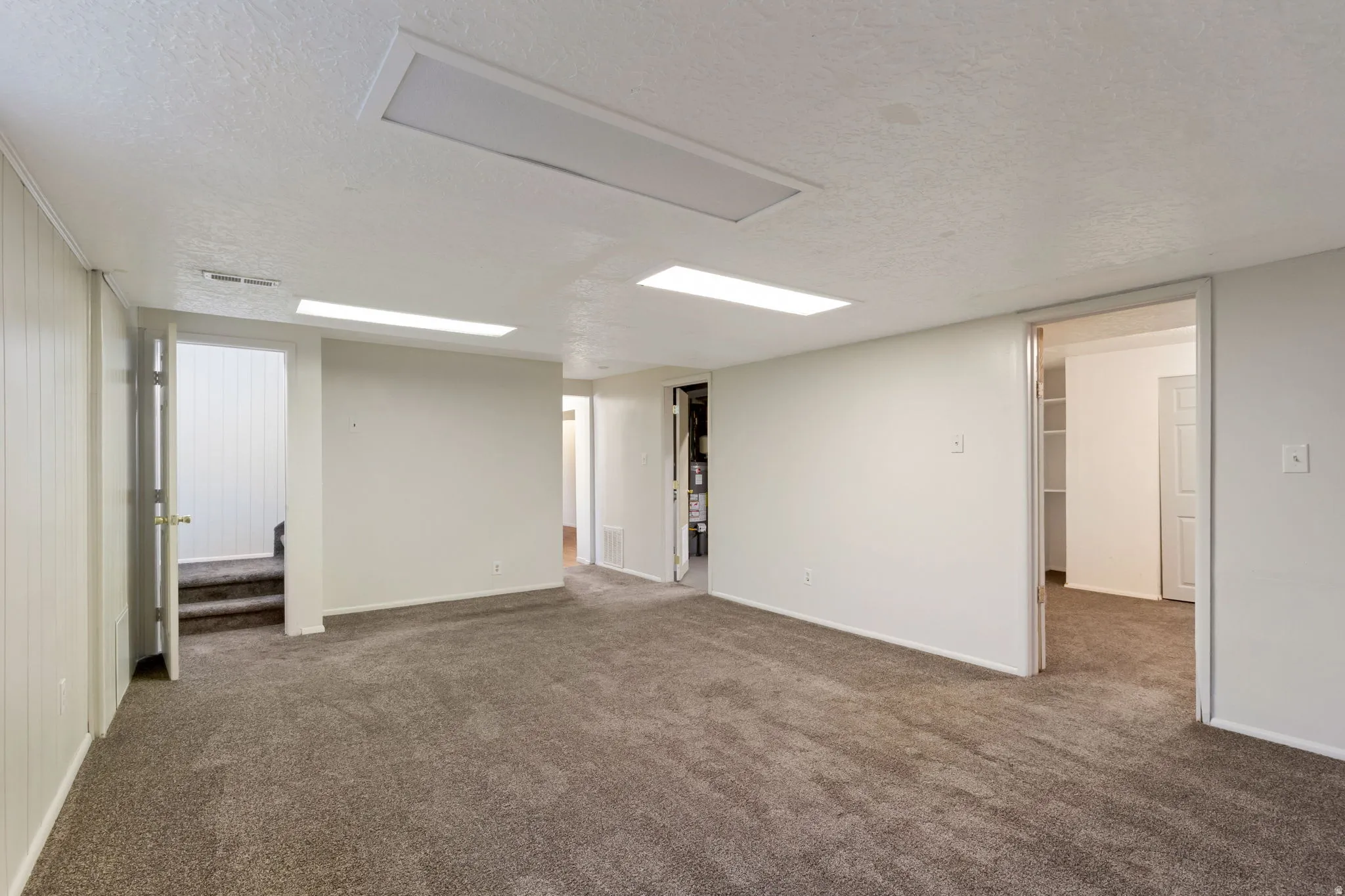 Spacious family room featuring neutral carpeting, white painted walls, recessed lighting, and multiple doorways