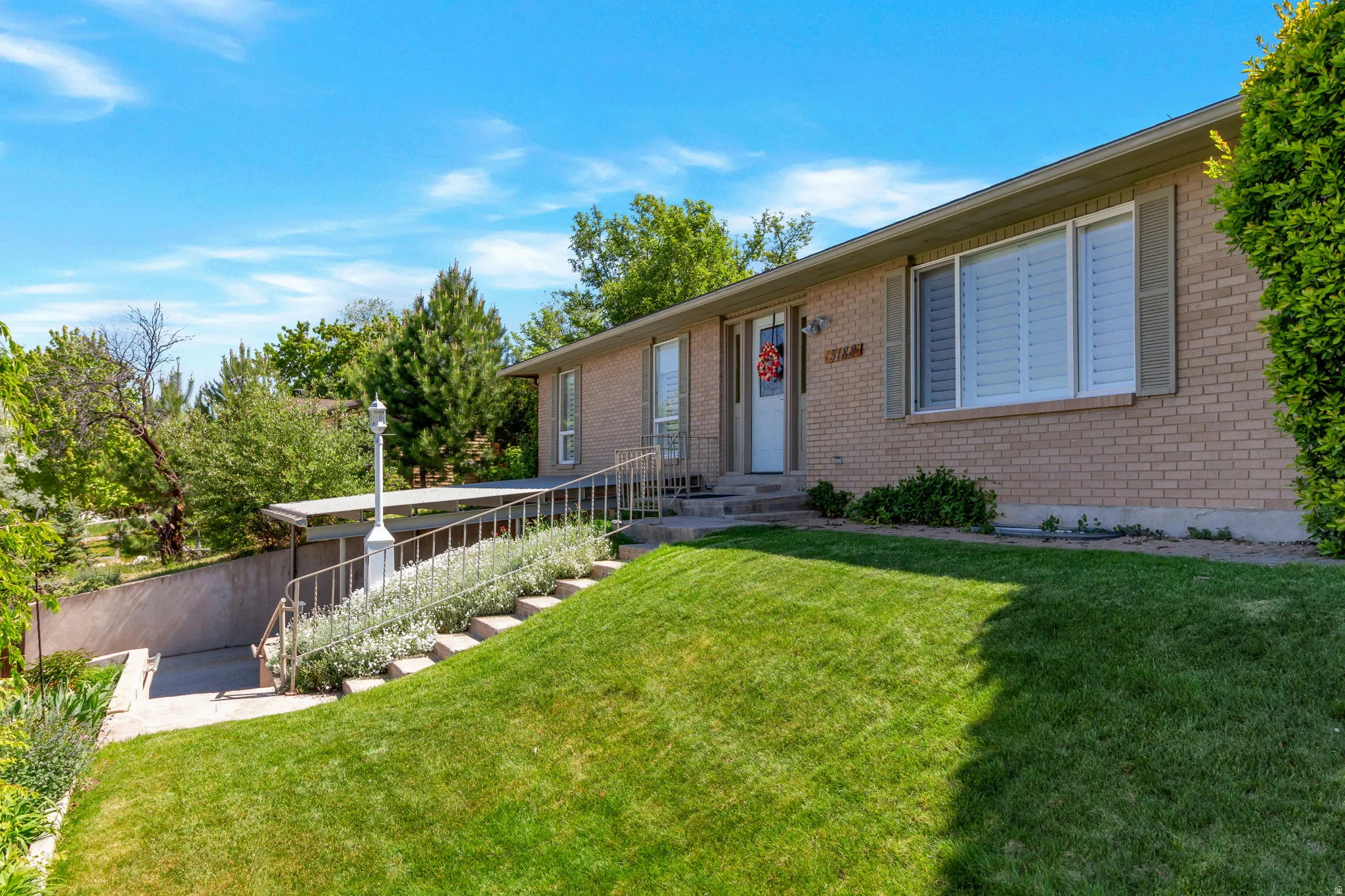 Brick exterior with entryway and a sloped front lawn