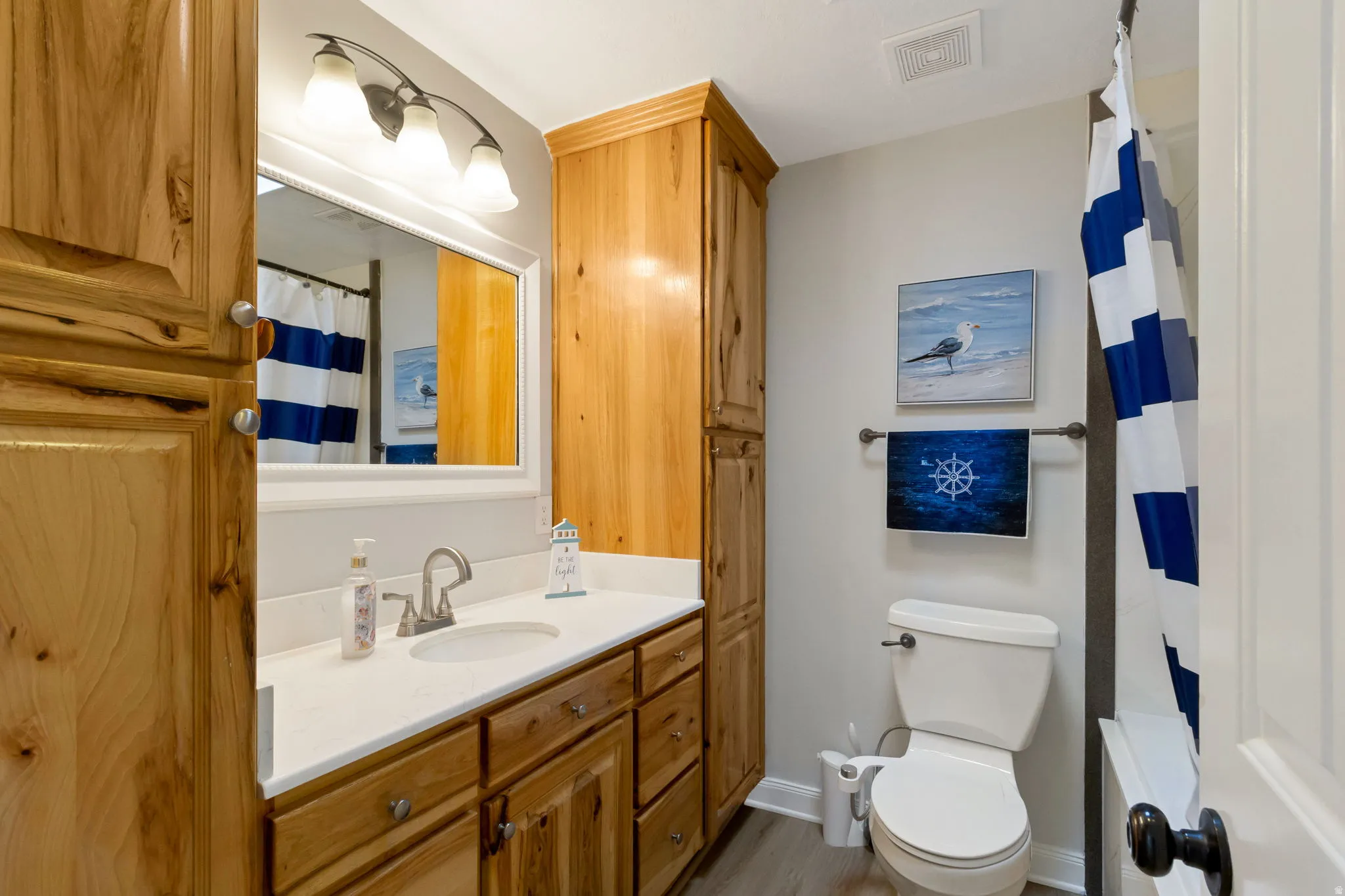 Bathroom featuring a wood-finish vanity with a white countertop and an undermount sink