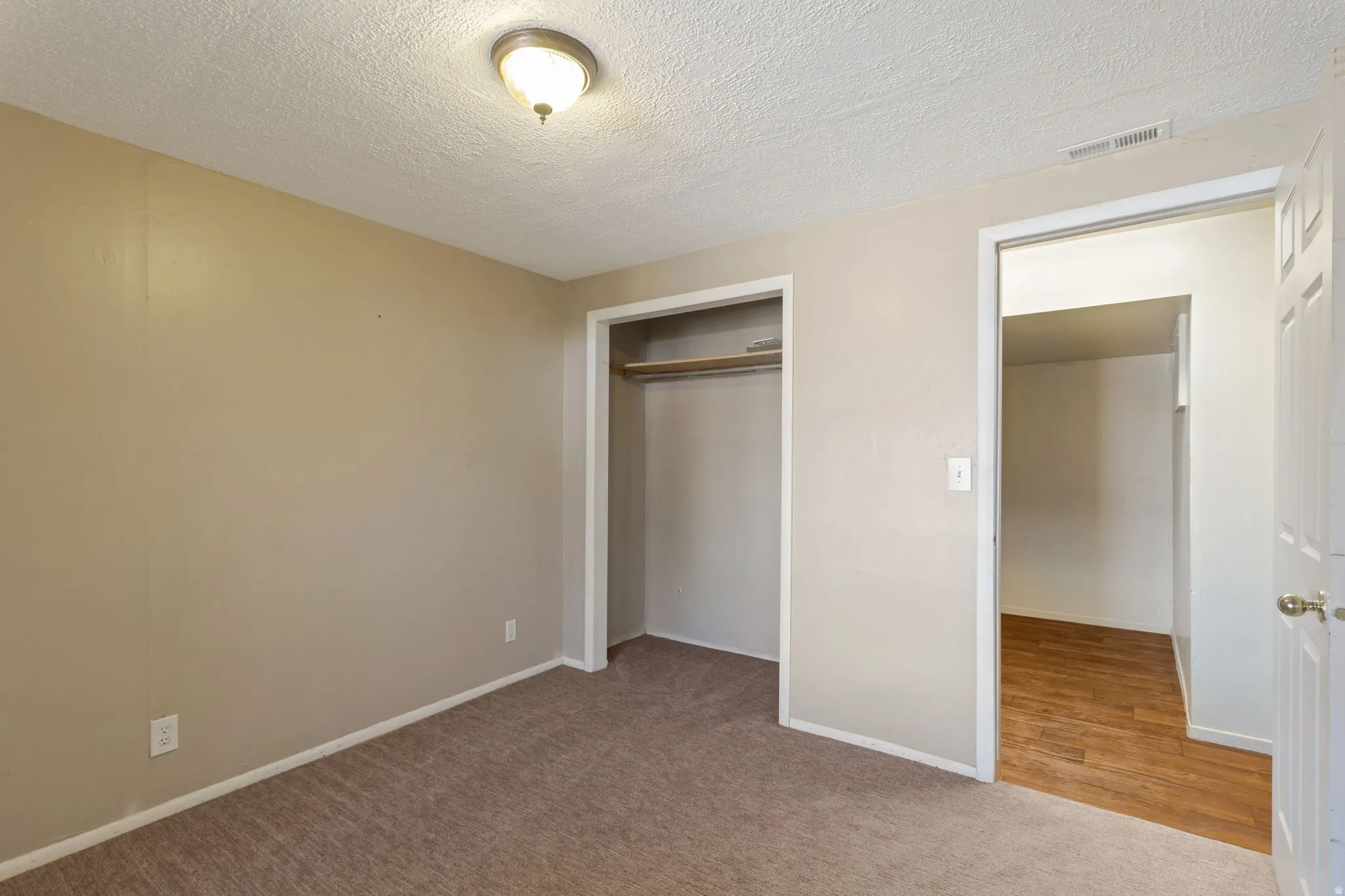 Carpeted room with neutral wall tones and a ceiling-mounted light fixture