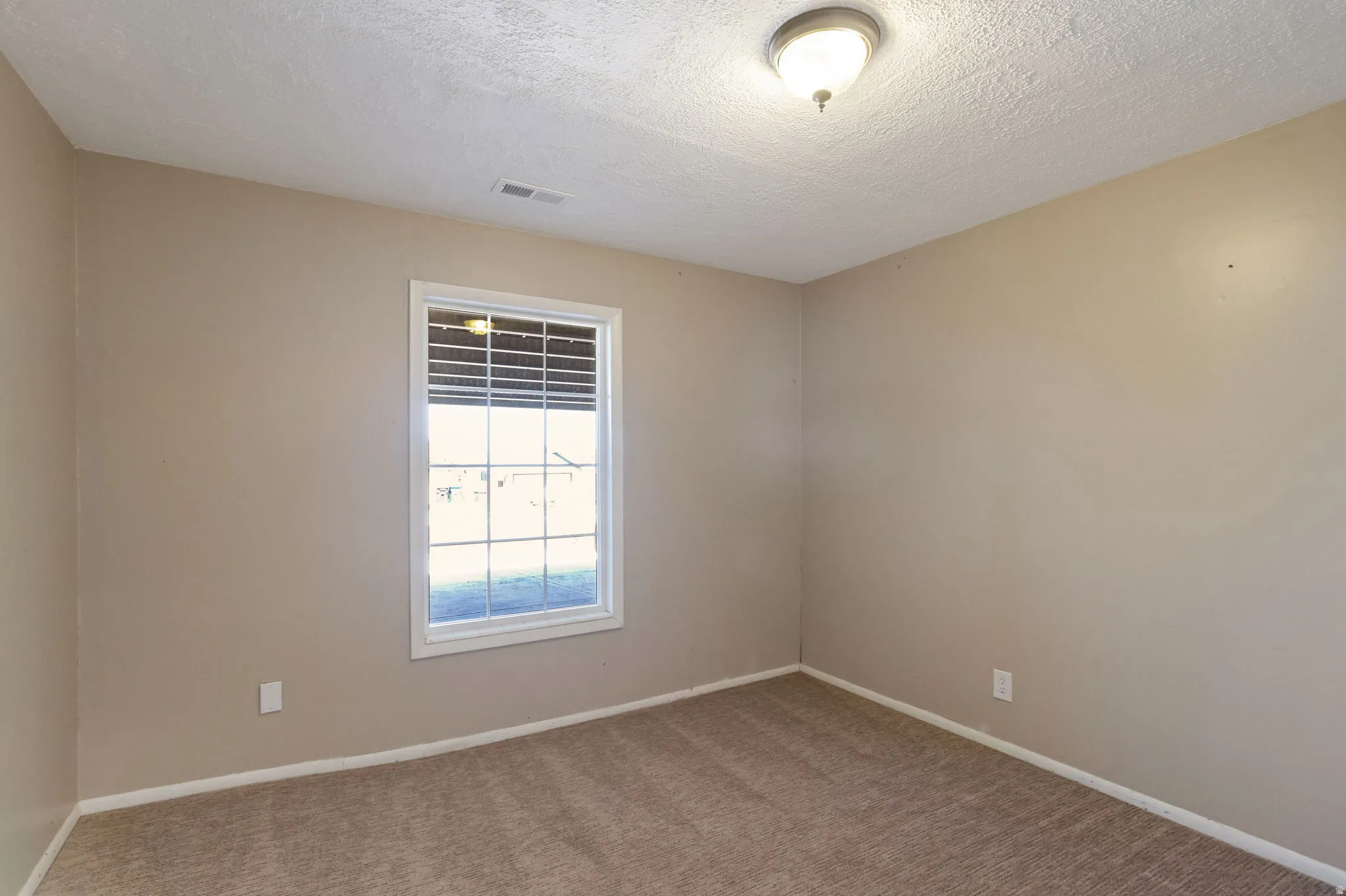 Room featuring neutral-toned carpet, a window with horizontal blinds, and a flush-mount ceiling light