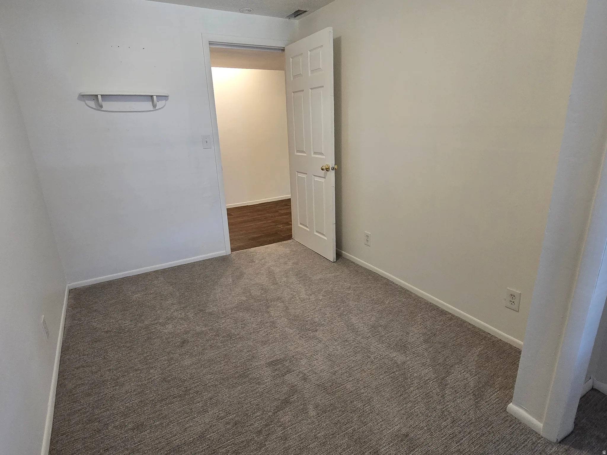 Neutral tone wall paint, carpeted flooring, white trim, and a white interior door