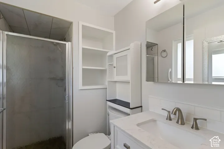 Bathroom featuring a glass-enclosed shower with tile surround, a built-in shelving unit, and a vanity with an undermount sink and brushed nickel faucet