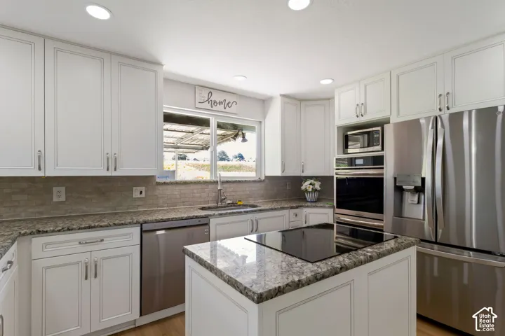 Contemporary kitchen featuring white cabinetry, stone countertops, a mosaic tile backsplash, and recessed lighting