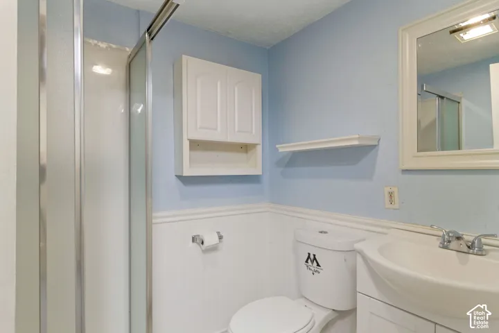 Bathroom featuring a glass-enclosed shower, wall-mounted storage cabinet, white vanity with integrated sink, and framed mirror