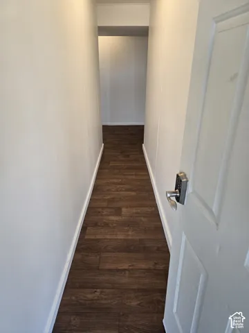 Hallway from the carport with wood-finish flooring, white walls, and white trim