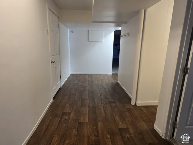 Spacious hallway flooring showcasing warm wood-finish planks throughout, complemented by clean white walls and multiple doorways providing access to adjoining rooms
