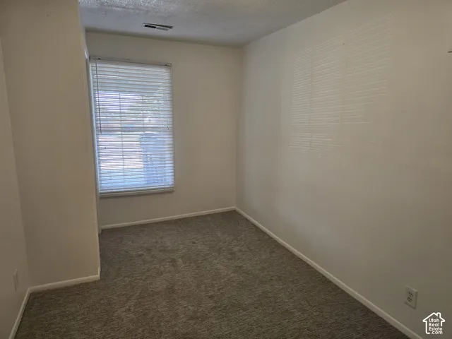 Carpet flooring, neutral painted walls, single window with blinds, and ceiling-mounted air vent
