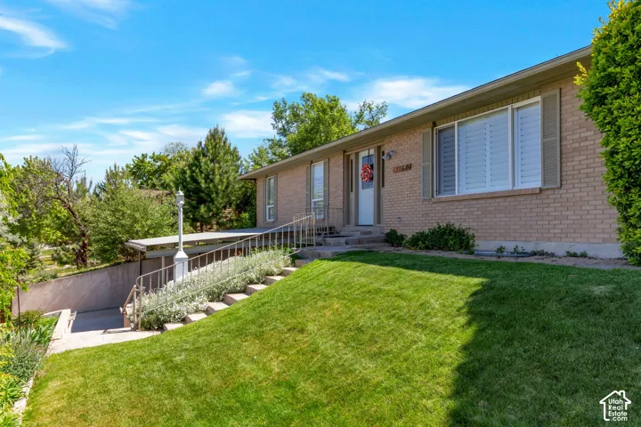 Brick exterior with entryway and a sloped front lawn