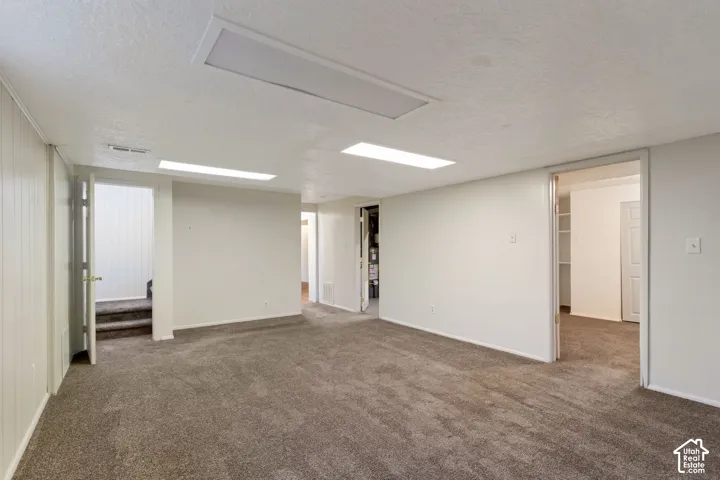 Spacious family room featuring neutral carpeting, white painted walls, recessed lighting, and multiple doorways