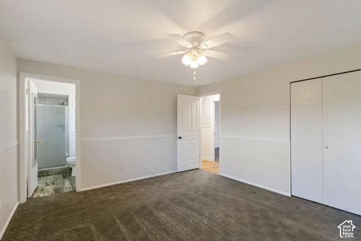 Carpeted bedroom featuring a ceiling fan with light fixture, chair rail molding, and panel doors