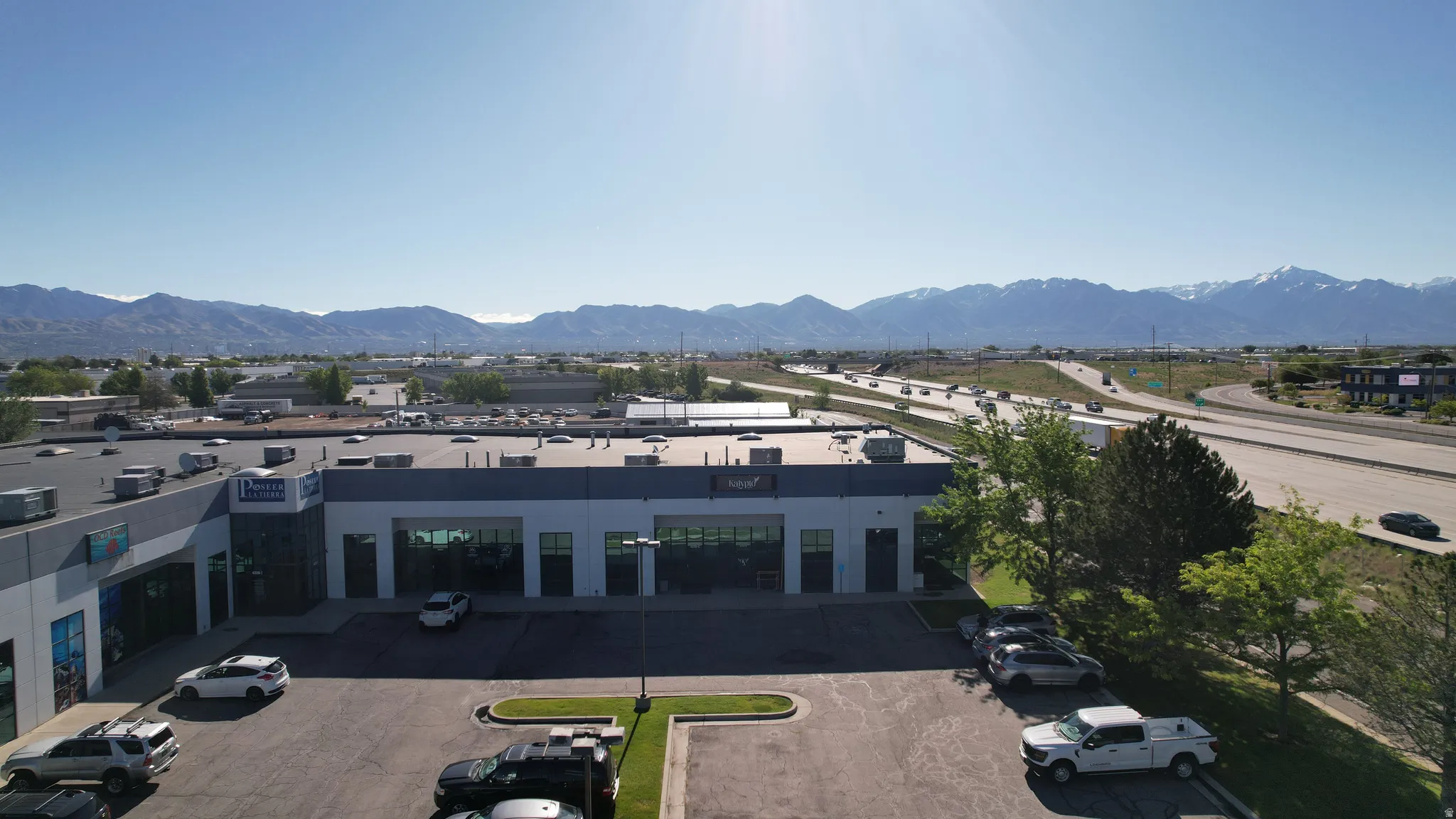 Commercial building featuring a dark gray and white exterior with multiple large windows, ample on-site parking, and direct highway frontage
